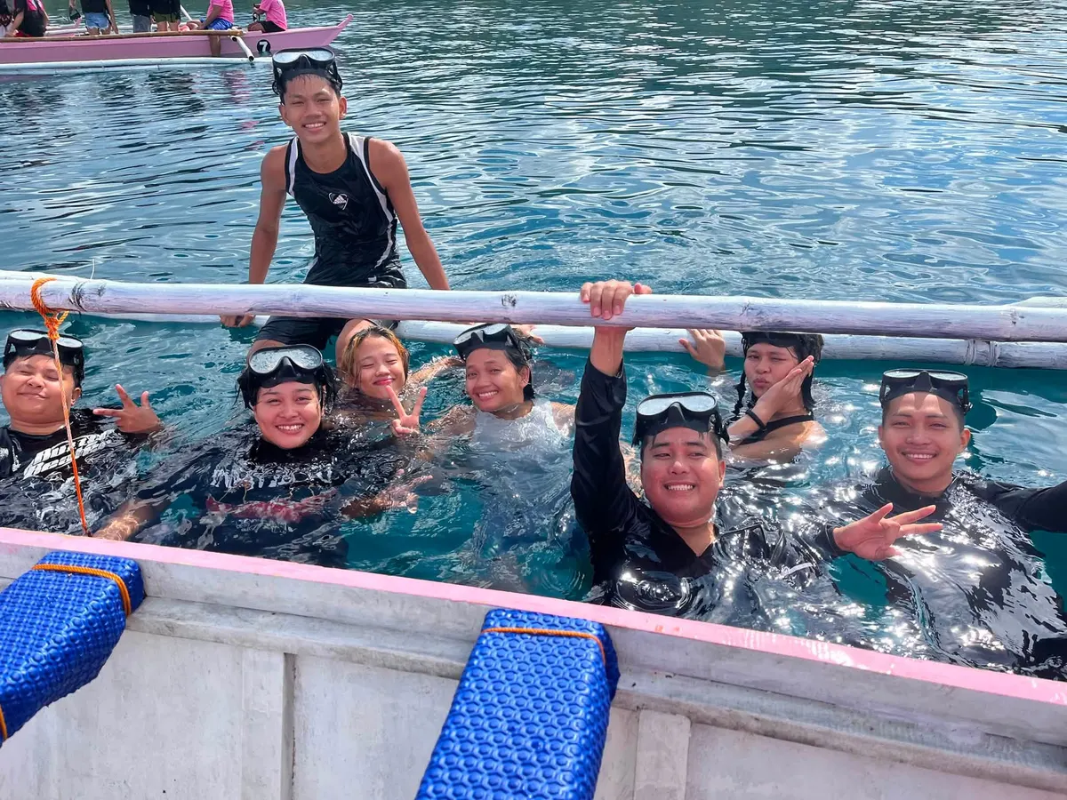 Guests smiling in the water beside a tour boat