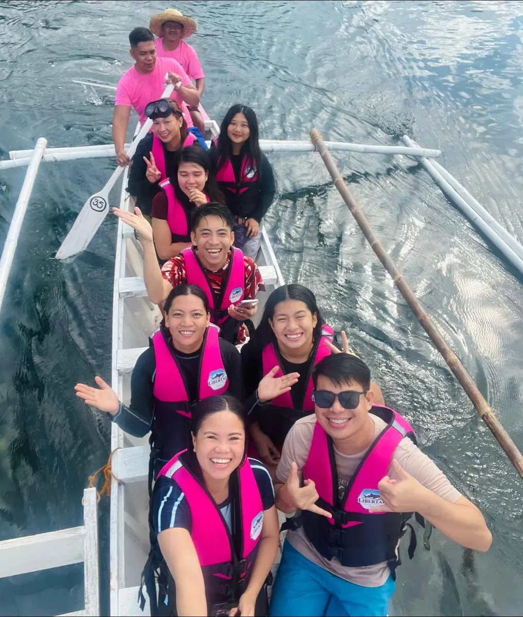 Guests posing in a boat beside a whale shark