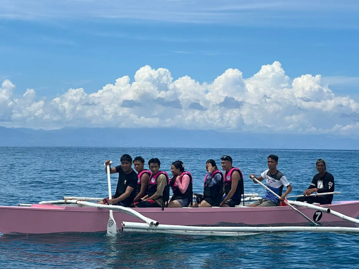 Tour group riding a pink boat under bright clouds