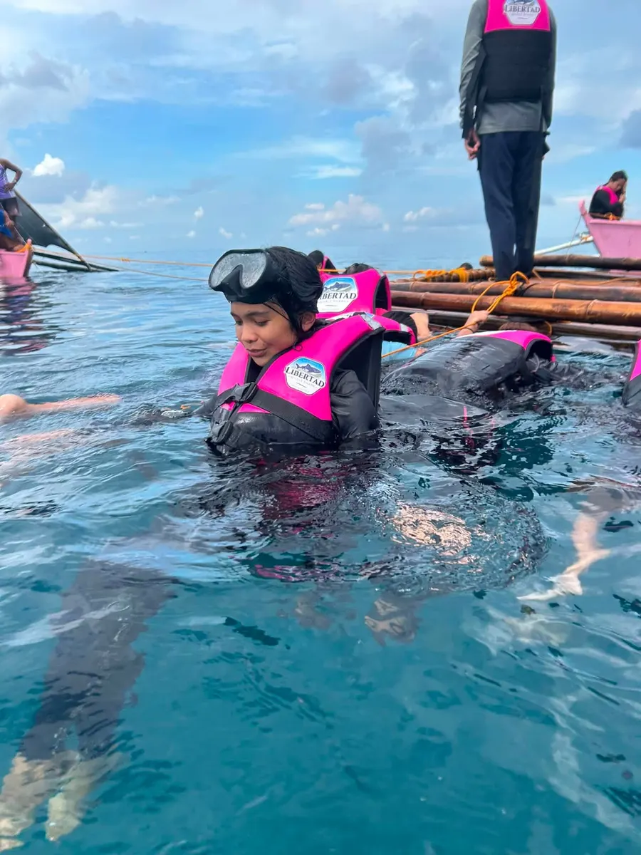 Child guest floating in the water near a raft